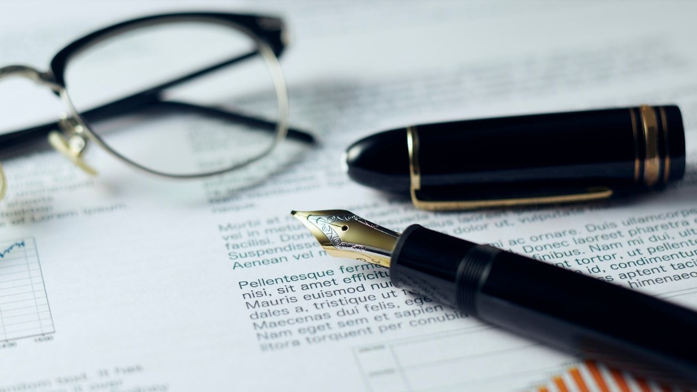 A fountain pen and a pair of glasses resting on a printed document with a chart.
